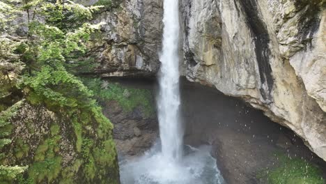 Waterfall-cascading-down-rocky-cliffs-surrounded-by-lush-greenery-in-Glarus-Süd,-Switzerland