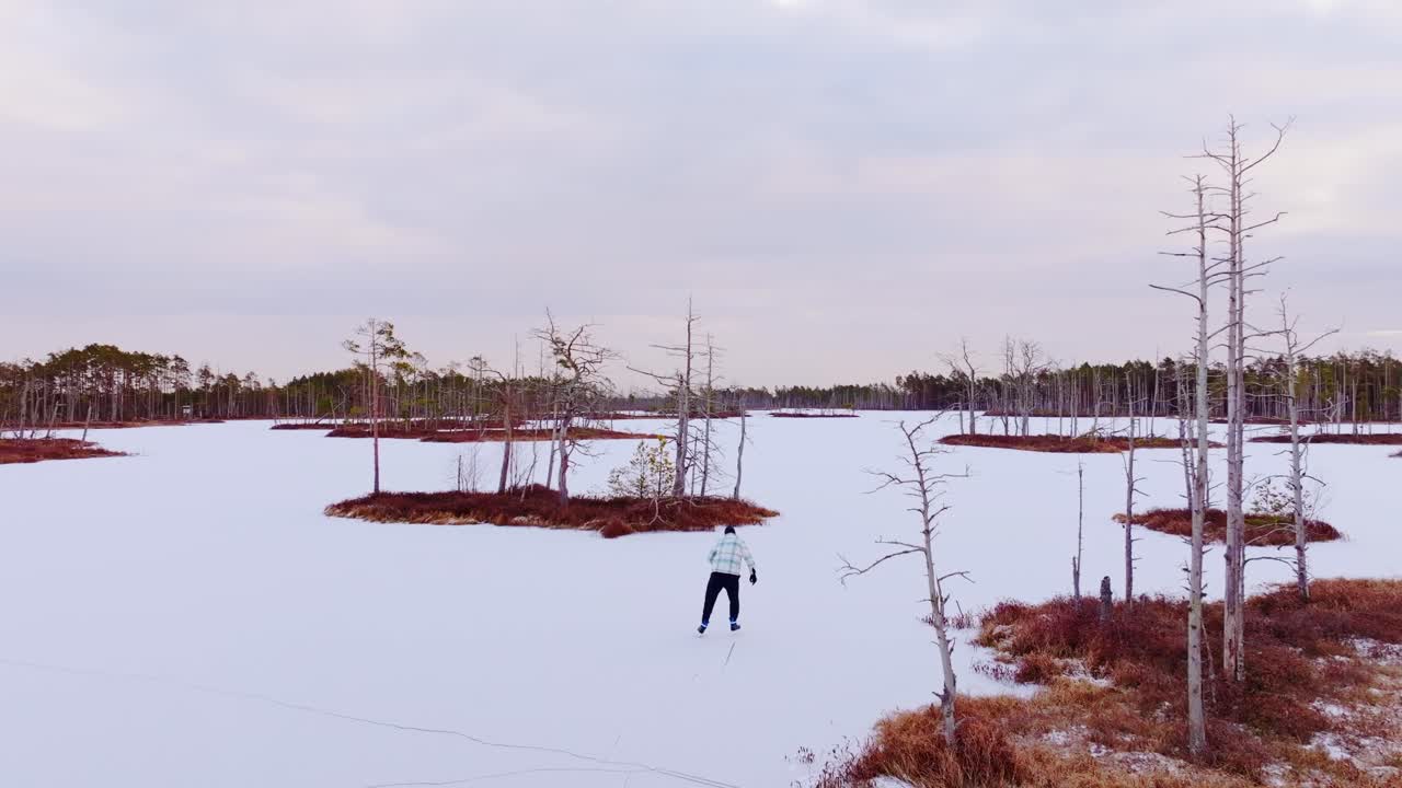 Early morning drone view of skater on frozen lake in scenic Cenas Bog, Latvia