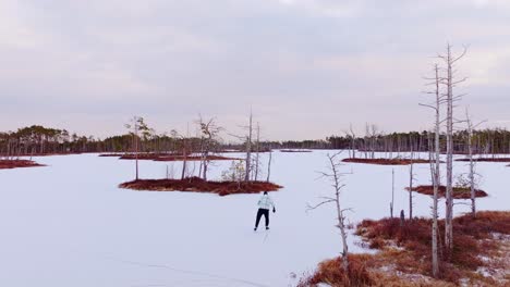 early morning drone view of skater on frozen lake in scenic cenas bog, latvia