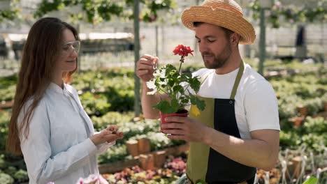 a female biologist hands a test tube with a solution to a young gardener man