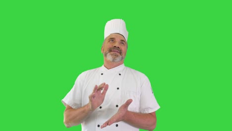 chef senior aplaudiendo a la cámara y sonriendo en una pantalla verde, clave de croma