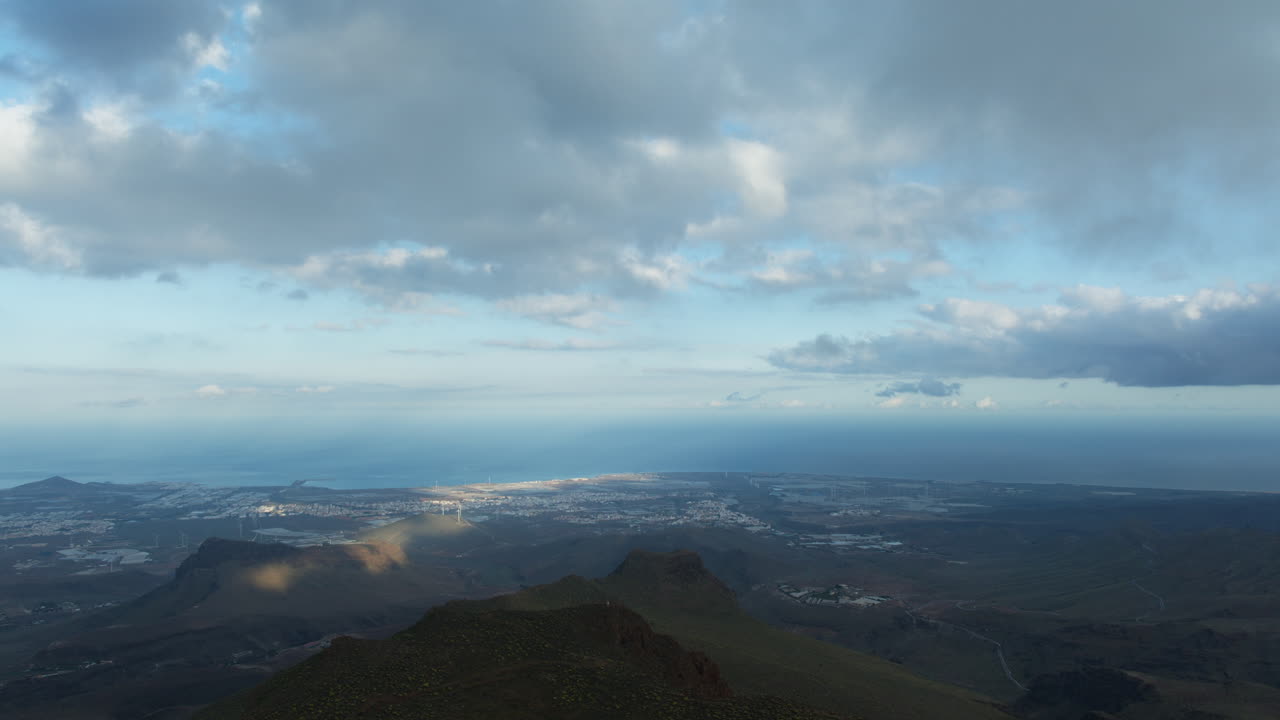 Clouds moving fast over a volcanic landscape and a city on the coast of Gran canaria, canary islands, spain