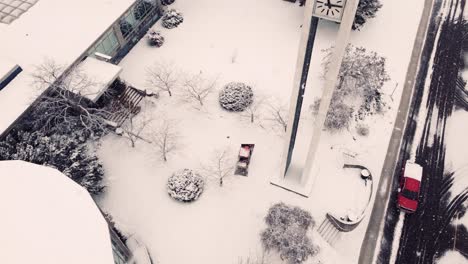 a mini bulldozer clears a sidewalk in front of a building during a snowstorm, winter