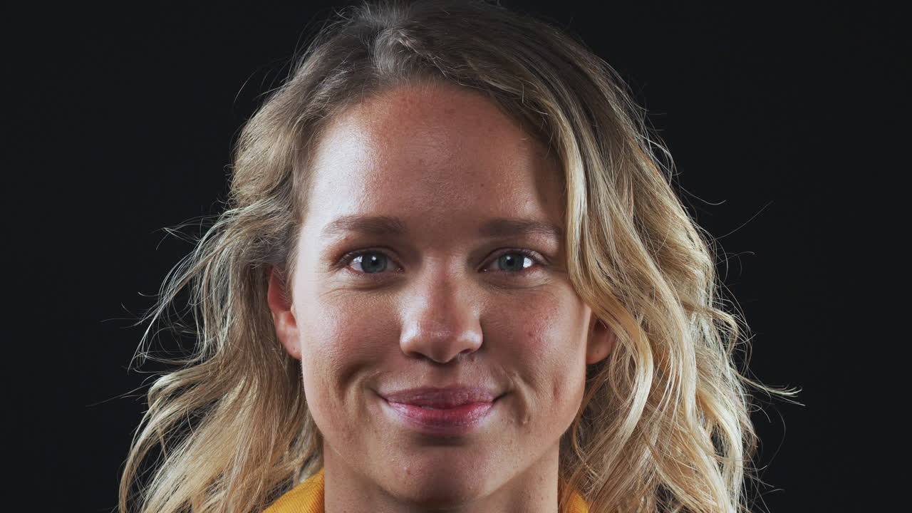 близко голова и плечи студийный снимок женщины, смеющейся над камерой в замедленном движении