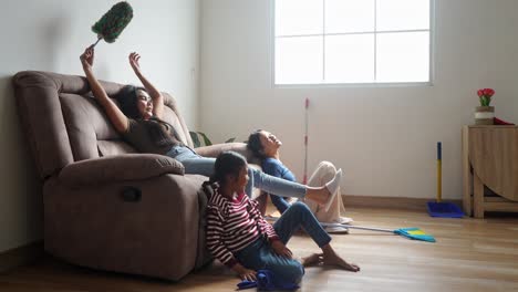 asian mother and daughters cleaning the house and sitting on sofa feel tired