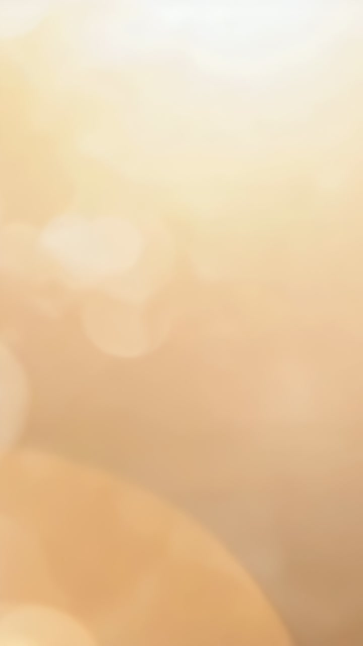 Video verticale: bokeh dorato in movimento che reagisce a un leggero spostamento della telecamera in un campo caldo, con bagliore dell'obiettivo visibile
