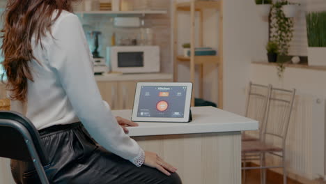 mujer mirando una tableta en una casa con sistema de iluminación automática