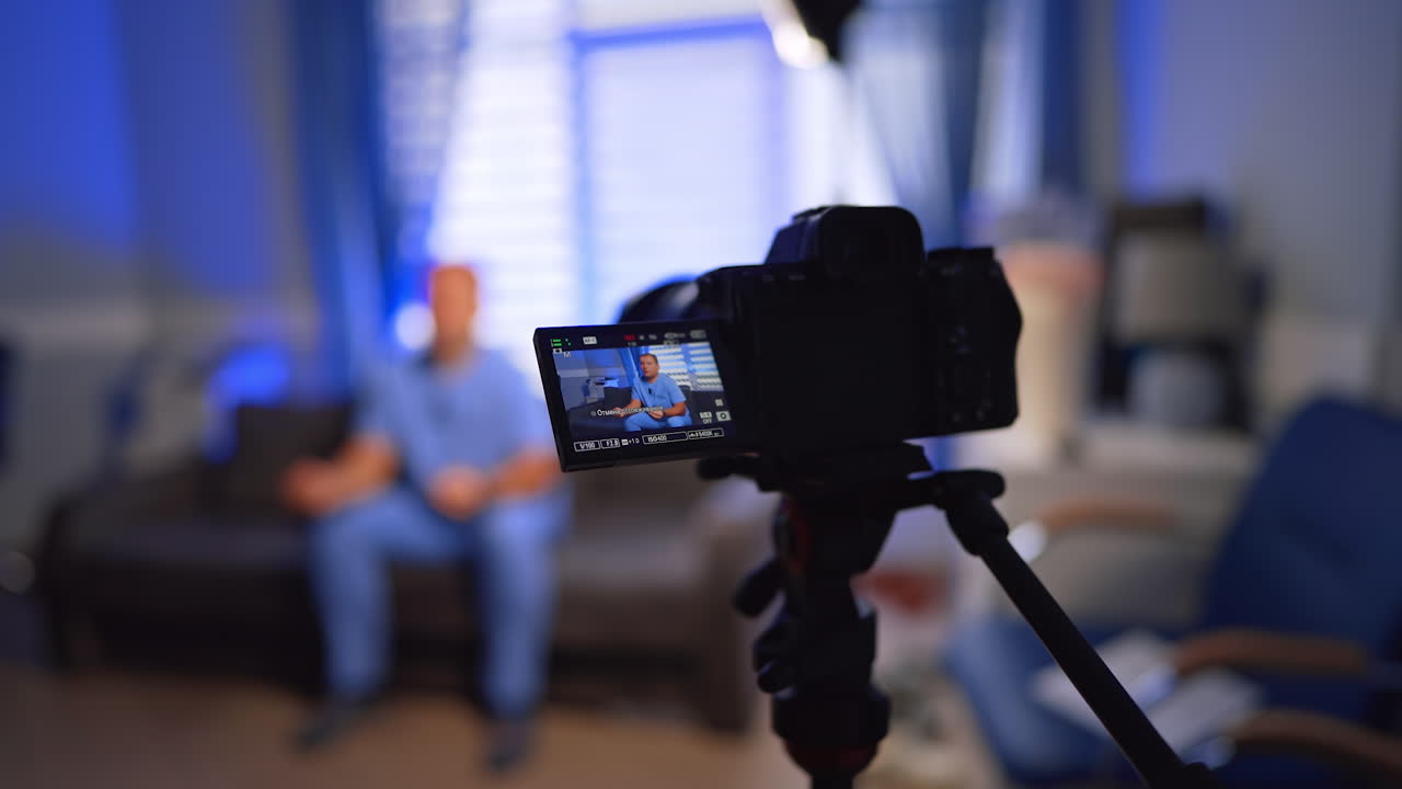 Telecamera con display che mostra il dottore in divisa blu. Creazione di video di contenuti medici in ufficio. Messa a fuoco selettiva