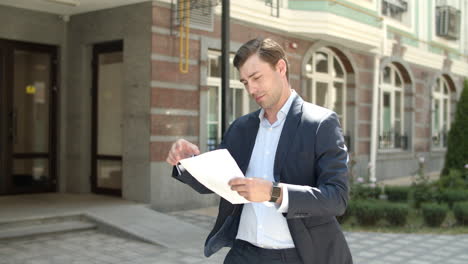 Retrato-Empresario-Leyendo-Documentos-Al-Aire-Libre.-Hombre-Tachonando-Papeles-En-La-Calle