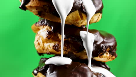 y profiteroles apilados con glaseado de chocolate y crema