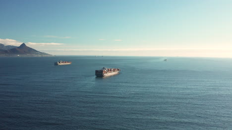 aerial view of cargo vessels with shipping containers traveling across the sea in daylight