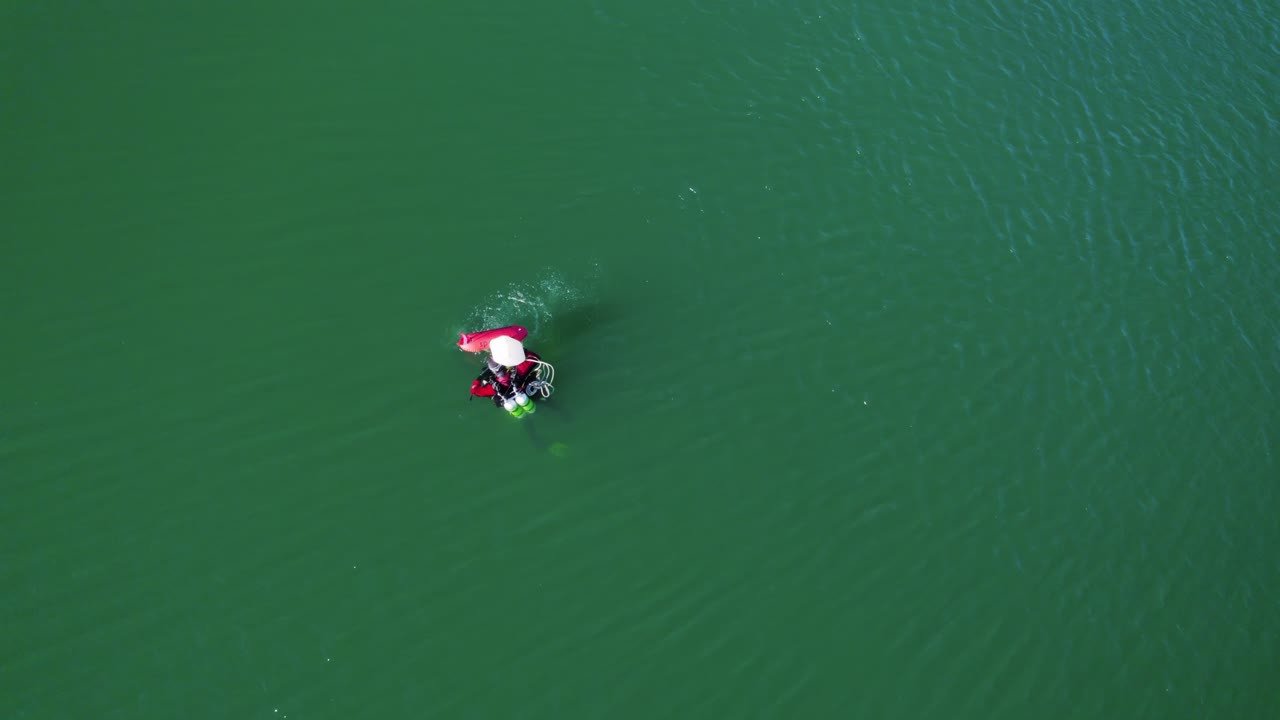 Top-down shot overhead of a diver on the surface with bubbles rising to the surface