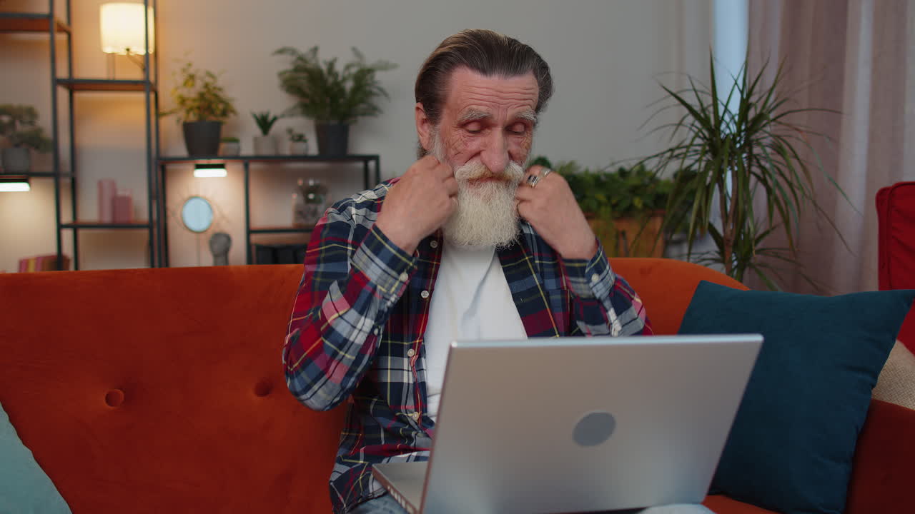 anciano abuelo hombre freelance trabajando en portátil, envía mensajes, hace compras en línea en casa