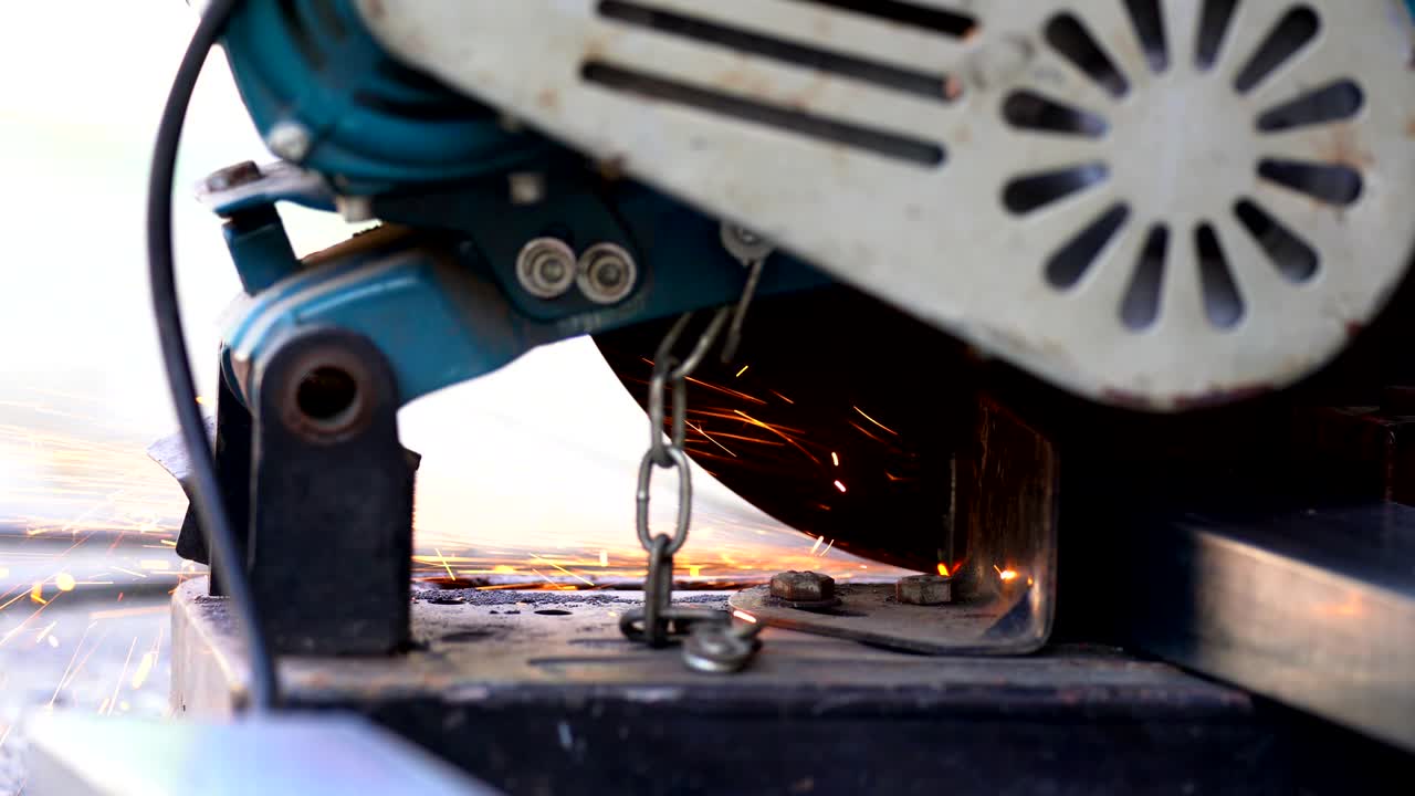 건설 노동자 용접기 손의 4k 클로즈업 은 철강 바를 절단하고 용접에서 불꽃을 만들기 위해 전기 각성 회전기를 사용합니다.