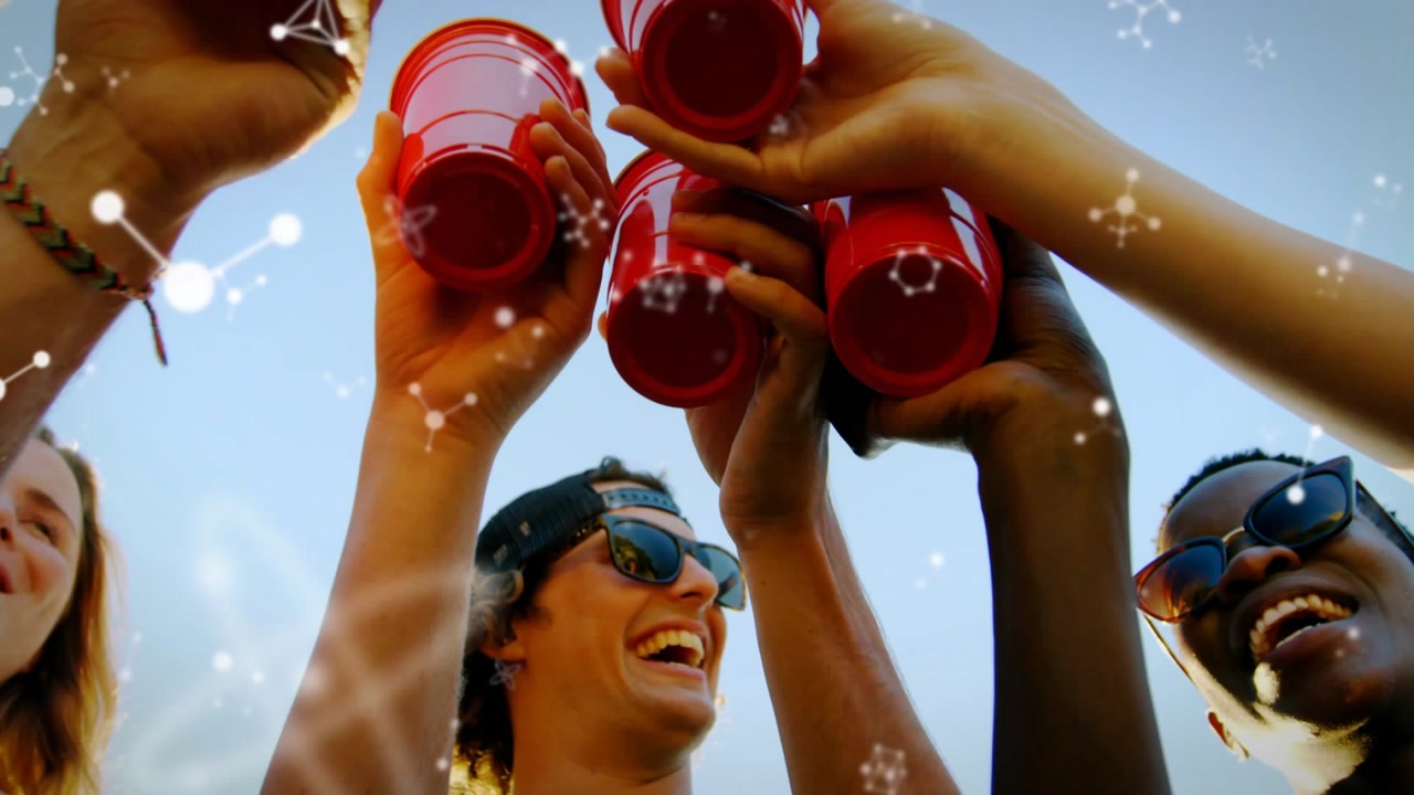 Friends bringing red cups above camera, clinking and drinking, toasting friendship as sun flaring