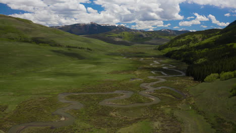 Antena-Alta-Del-Sinuoso-Río-East-Al-Este-De-La-Montaña-Crested-Butte-Con-Doble-Cima-Al-Norte-Y-Al-Sur-En-El-Fondo---Primavera