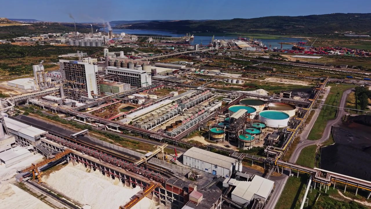 Industrial site along the river with large structures and storage areas