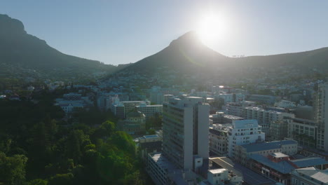 Town-development-and-Lions-Head-mountain-against-bright-sun.-Forwards-fly-above-buildings-in-City-Bowl.-Cape-Town,-South-Africa