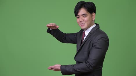 무언가를 보여주는 젊은 잘생긴 아시아 사업가