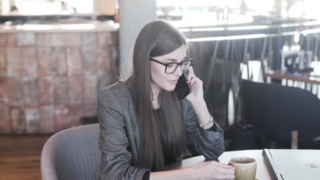 Frau-Im-Café-Sitzt-An-Einem-Tisch-Und-Telefoniert