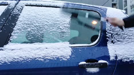 limpiando la nieve de un auto azul