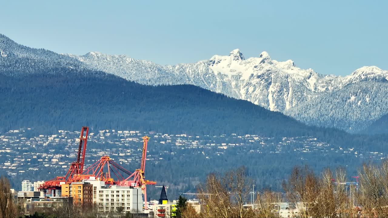 montañas escarpadas cubiertas de nieve desde el puerto industrial en vancouver, bc, canada