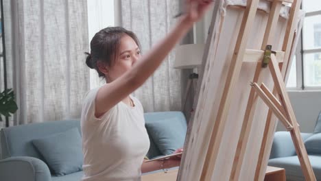 talented female artist energetically, enthusiastically using paint brush she creates with oil painting. creative studio with canvas