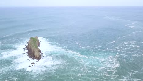 toma aérea de la isla rocosa billano irla con olas rompiendo en el océano