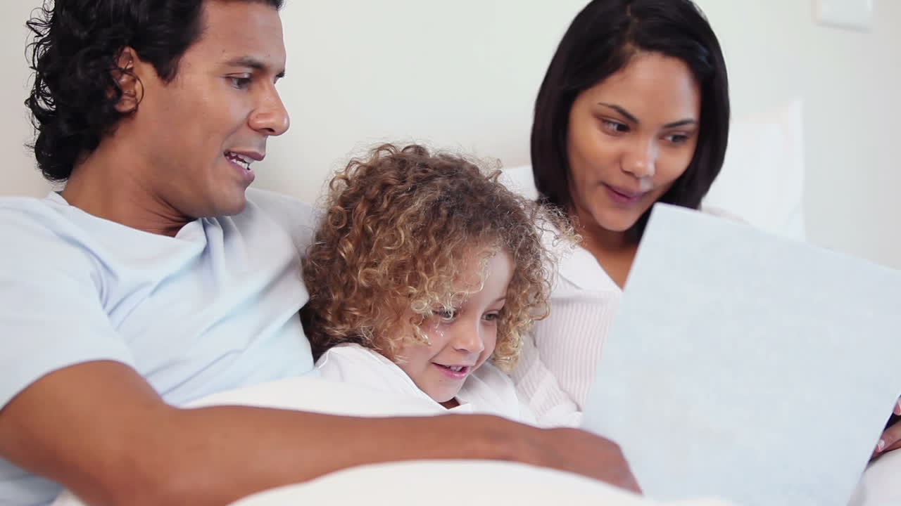 Família com um livro sentada na cama