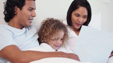 familia con un libro sentado en su cama