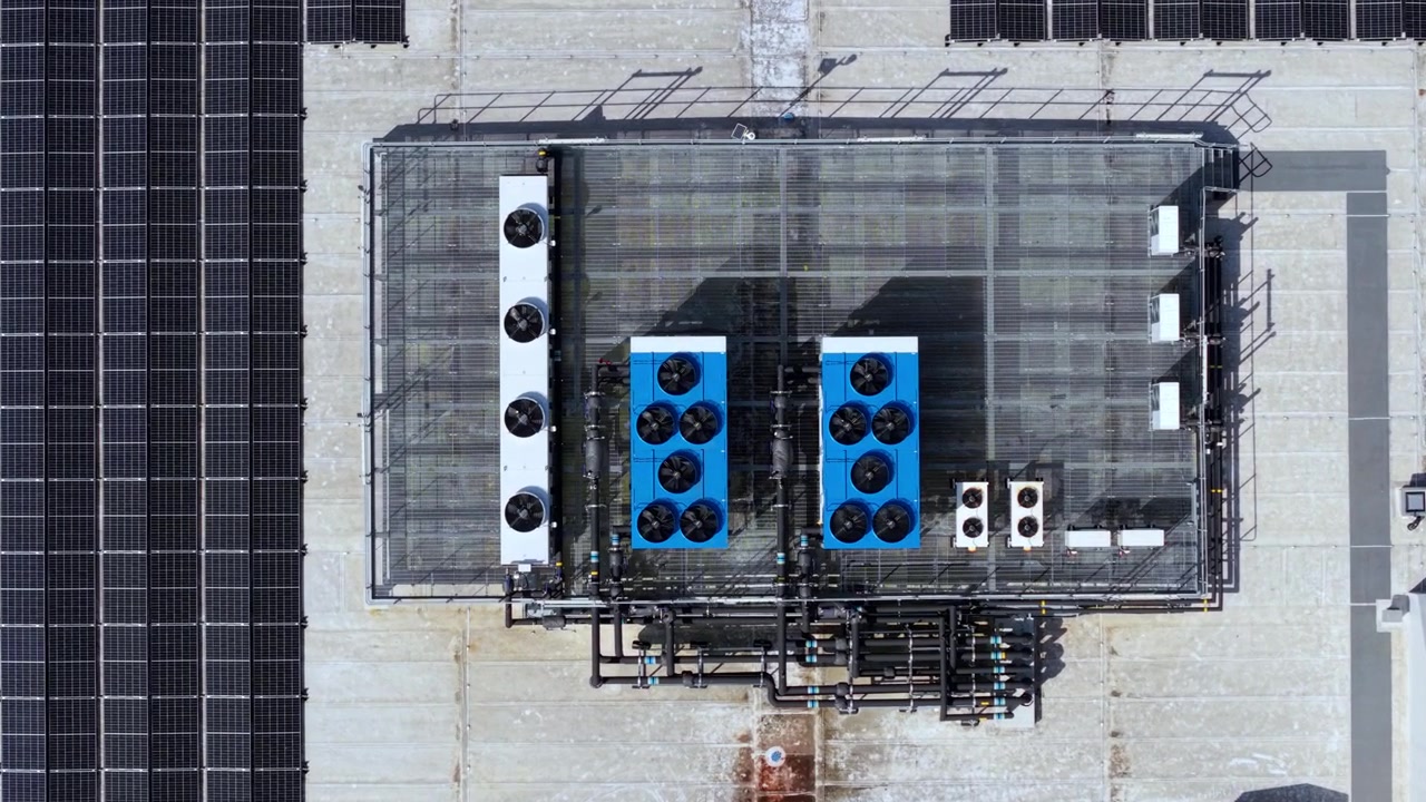 Overhead Close Up Drone View of Industrial Roof Solar Panel Installation and Cooling Duct Infrastructure