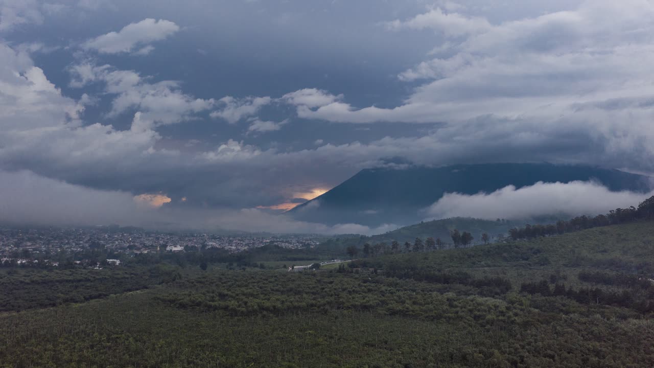 Hyperlapse aereo con drone diretto verso 2 vulcani attivi durante il tramonto in una giornata nuvolosa, con panoramica su un altro vulcano situato ad Antigua Guatemala in America Centrale in 4k