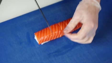 el chef está preparando un rollo de sushi de salmón.