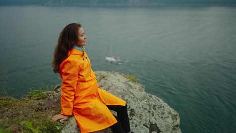 woman in orange rain jacket by the lake