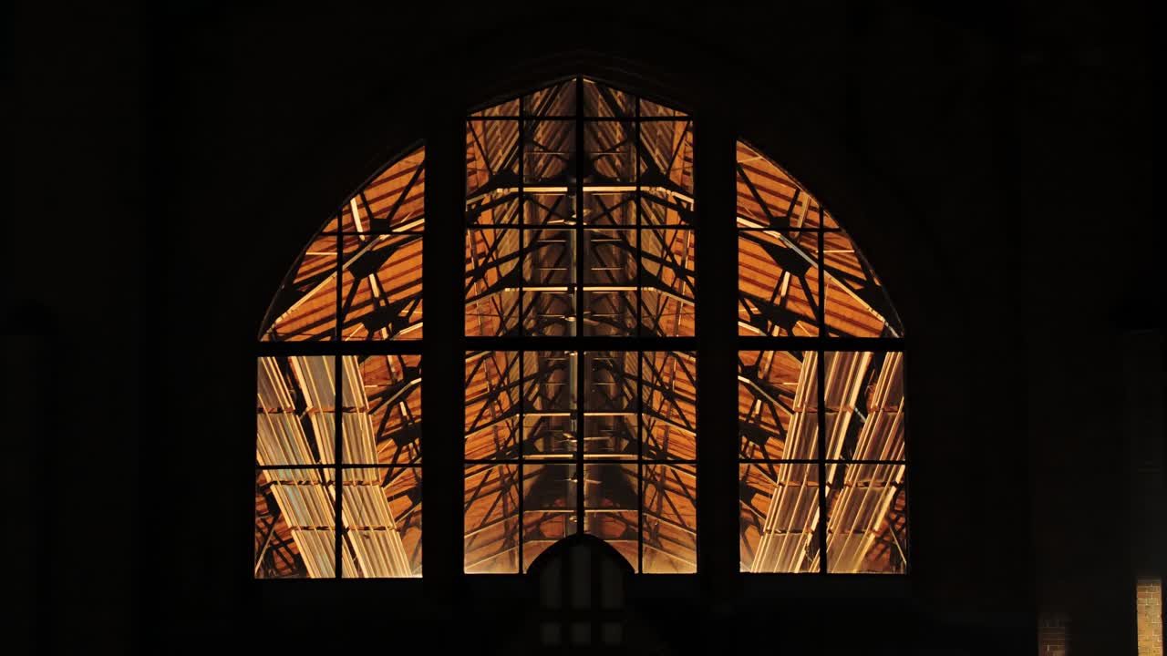 Interior lights and ventilation fans glow inside Āgenskalns market on dark night