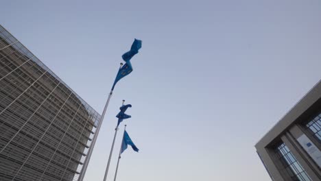 european flags flap in the wind between the buildings of the european commission and the european council in brussels, belgium - low wide angle