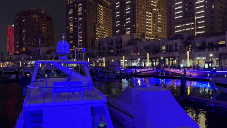 Yacht-luxury-expensive-boat-in-the-club-in-Doha-Qatar-Garmin-navigation-system-in-the-sea-water-tower-hotel-buildings-in-the-background-at-night-in-pearl-lulu-mall-qanat-quartier-island-katara-lusail