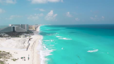 drone ascends over cancún’s hotel zone showing beachfront resorts, white sand, and vivid turquoise caribbean sea