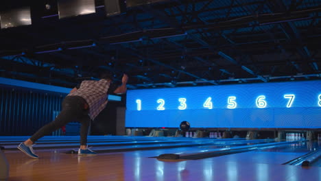 Caucasian-Man-in-bowling-throws-a-ball-in-slow-motion-and-knocks-down-skittles.-Play-bowling.-Throw-balls-on-the-floor-of-the-bowling-club