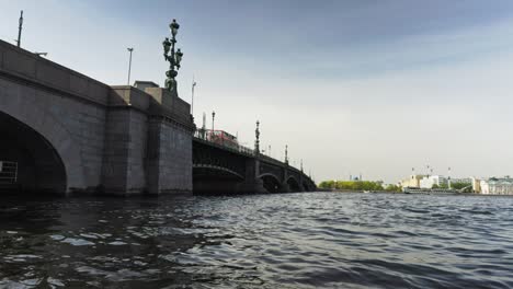 drawbridge over the river, walking tourists and a passing bus, water surface with waves