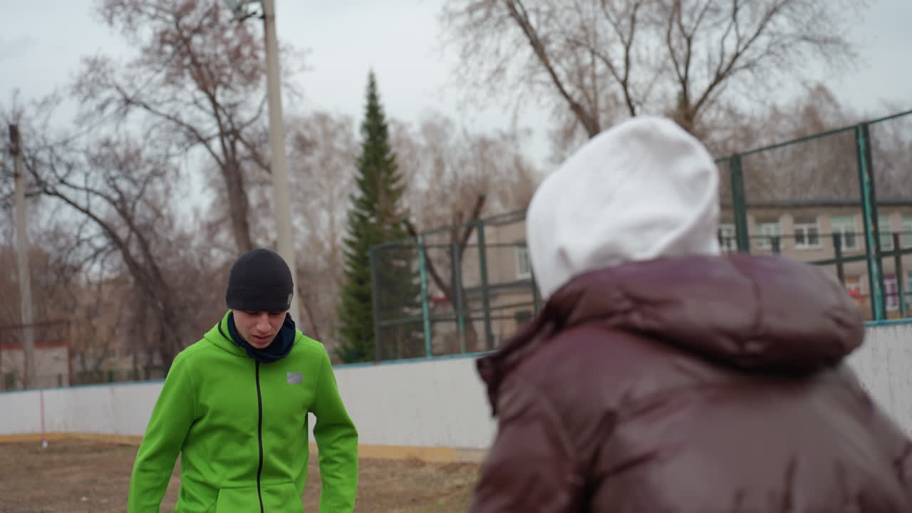 Тщательное руководство тренера для спортсменки, крупный план инструктора, практикующего передачи с игроком женского пола на открытом воздухе, городская футбольная обстановка, где тренер обучает точным касаниям при передаче и навыкам тайминга.