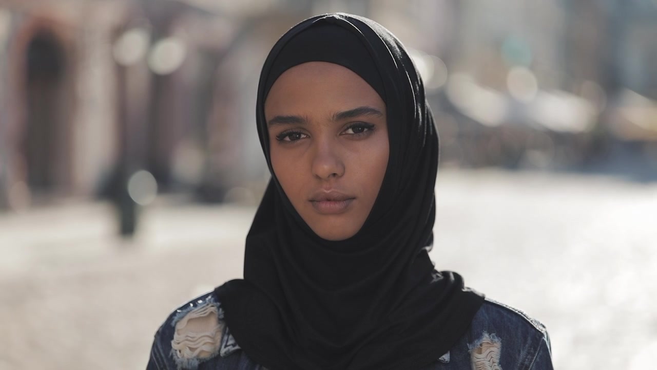Retrato de una mujer joven con hiyab negro en la ciudad