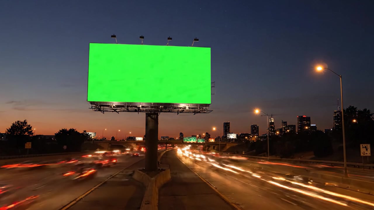 Valla publicitaria iluminada en carretera que pasa de verde en blanco a anuncio activo al anochecer, mostrando luces vibrantes de la ciudad y movimiento dinámico del tráfico