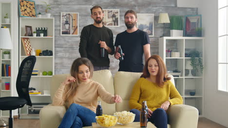 Amigos-En-La-Sala-Comiendo-Patatas-Fritas-Y-Hablando-Del-Partido-En-La-Televisión