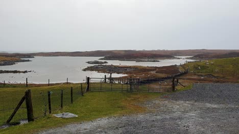 A-wet-and-raining-day-in-rural-countryside-of-Outer-Hebrides-overlooking-croft-farm-land-and-lake-loch-water-in-Scotland-UK