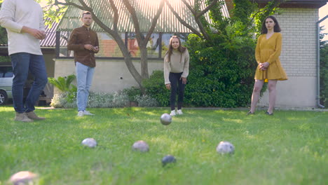 vorderansicht der kaukasischen jungen frau, die an einem sonnigen tag einen pétanque-ball im park wirft