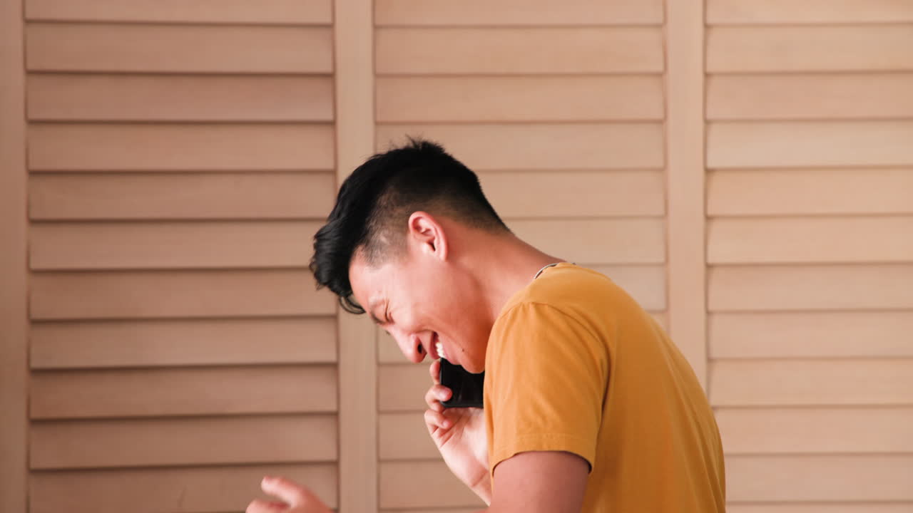 Smiling man at home talking on smartphone, enjoying casual conversation, copy space
