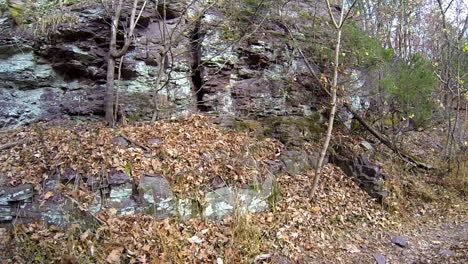 Steadicam-shot-moves-along-trail-next-to-rock-outcrop