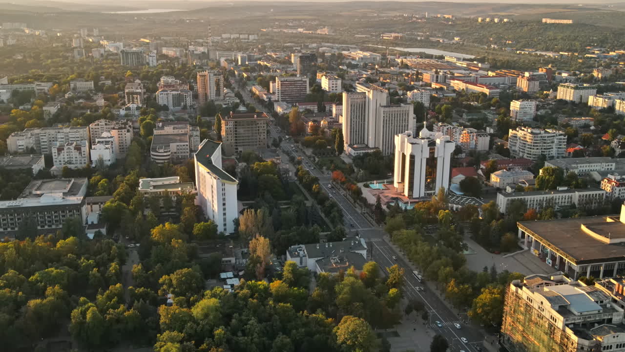 Aerial drone view of Chisinau downtown at sunset. Panorama view of multiple buildings, Parliament, Presidency, roads with moving cars and lush trees. Moldova