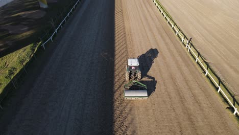Aerial-follow-through-shot-of-roller-tied-with-tractor-used-for-compaction-of-soil-at-the-race-course-track